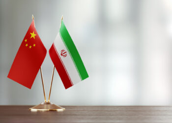 chinese and iranian flag pair on a desk over defocused background