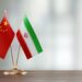 chinese and iranian flag pair on a desk over defocused background